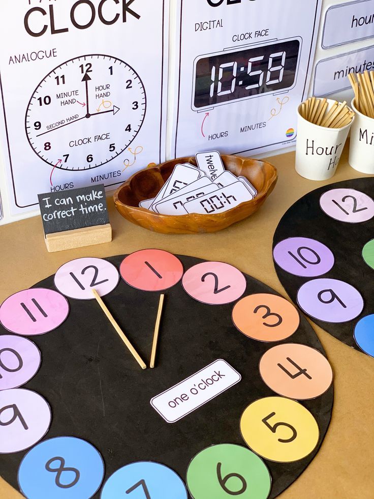 a clock made out of paper with numbers on the front and sides, sitting next to other clocks