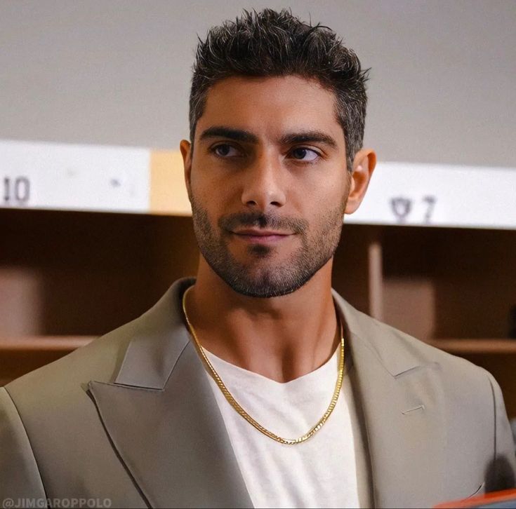 a man in a suit and necklace looking at the camera