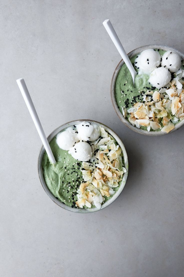 two cups filled with green smoothie and toppings