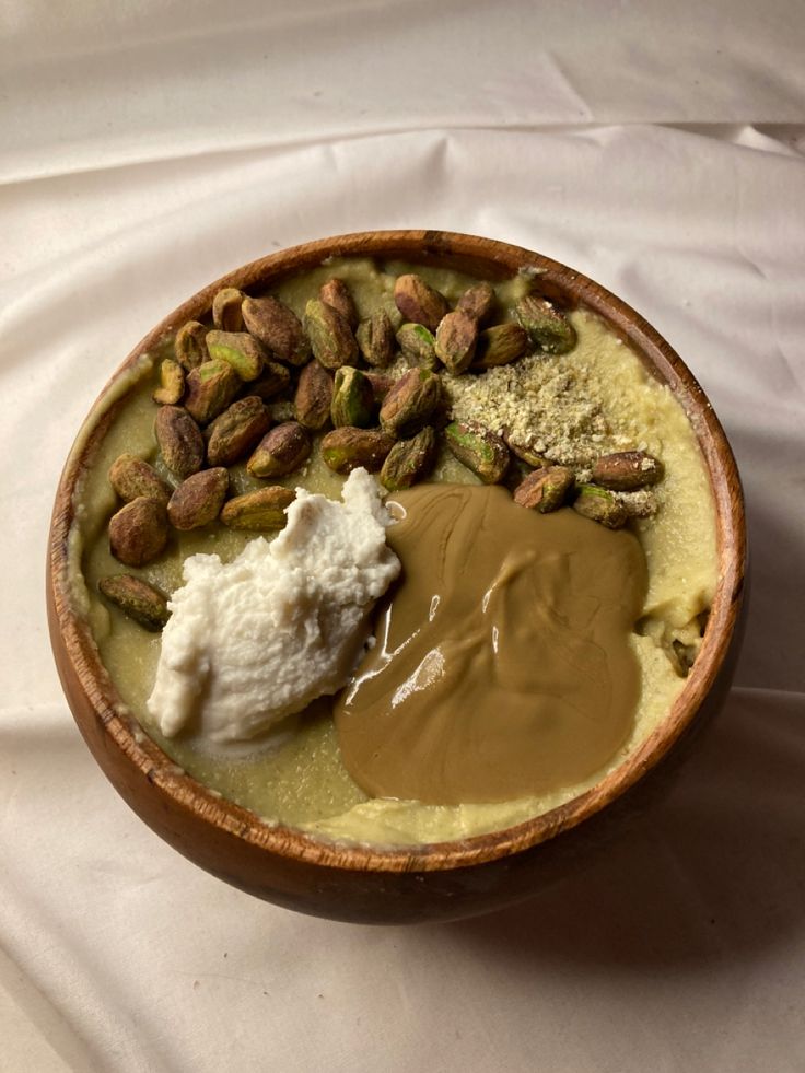 a bowl filled with pudding and nuts on top of a white cloth covered tablecloth