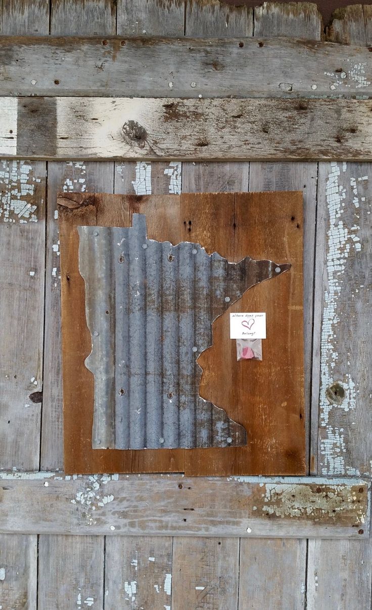 an old wooden door with peeling paint on it and a piece of metal in the middle