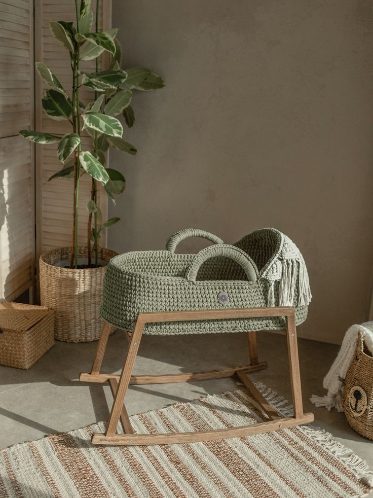 a baby's rocking chair sitting on top of a rug next to a potted plant