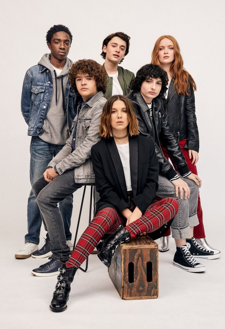 a group of young people sitting next to each other in front of a white background