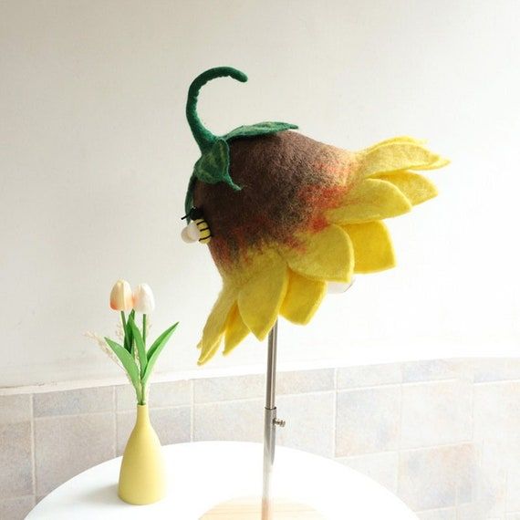 a fake sunflower sitting on top of a table next to a vase