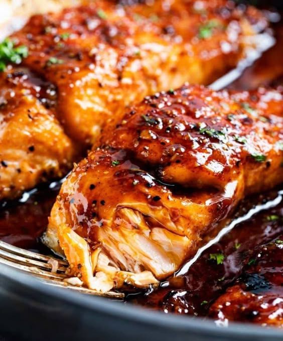 some chicken wings with sauce and parsley on the side in a black bowl, ready to be eaten