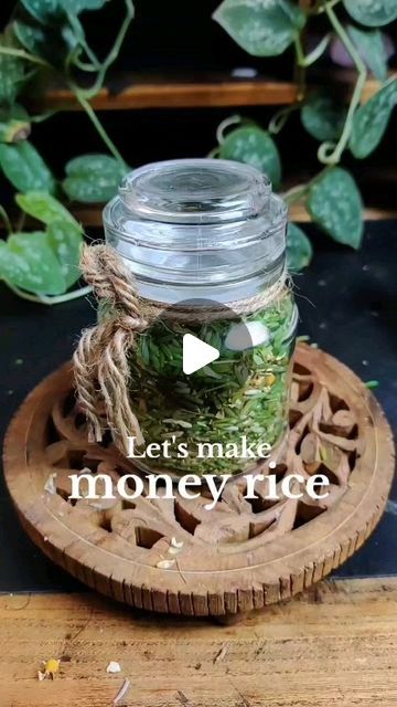 a glass jar filled with money sitting on top of a wooden tray next to a plant