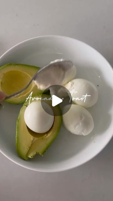 an avocado is cut in half on a white plate with a spoon and knife