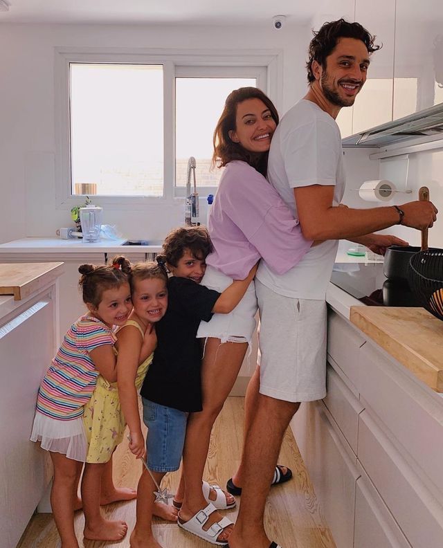 a man and two children are standing in the kitchen with their arms around each other