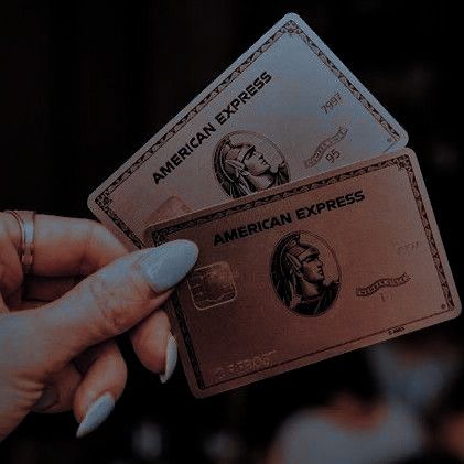 a woman holding two american express cards in her hand