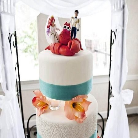 a three tiered wedding cake with crab figurines on top