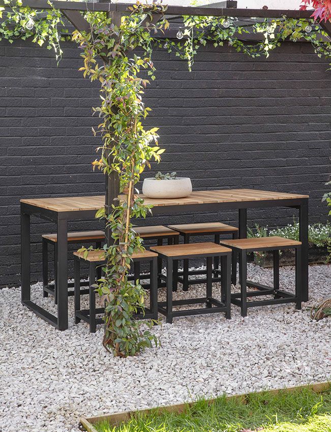 an outdoor table with four benches and a potted plant