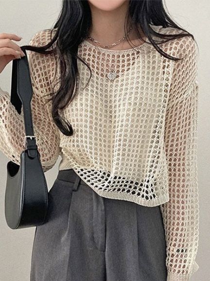 a woman holding a black purse in her right hand and wearing a white shirt with crochet on it