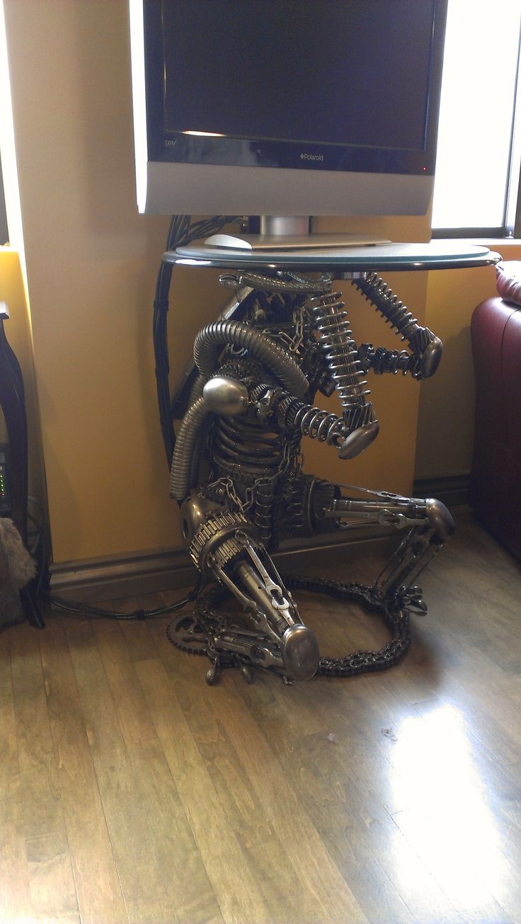 a metal sculpture sitting on top of a hard wood floor next to a flat screen tv