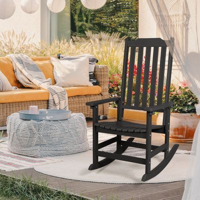 a rocking chair sitting on top of a white rug next to a couch and table