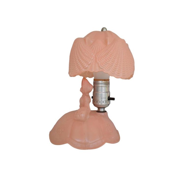 a pink lamp sitting on top of a white table next to a light fixture with a glass shade