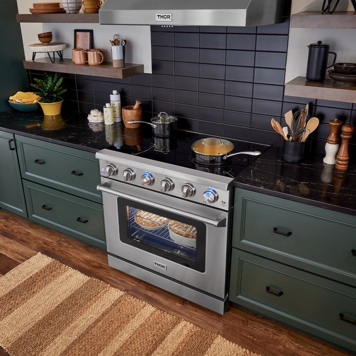 a stove top oven sitting inside of a kitchen next to green cupboards and counter tops