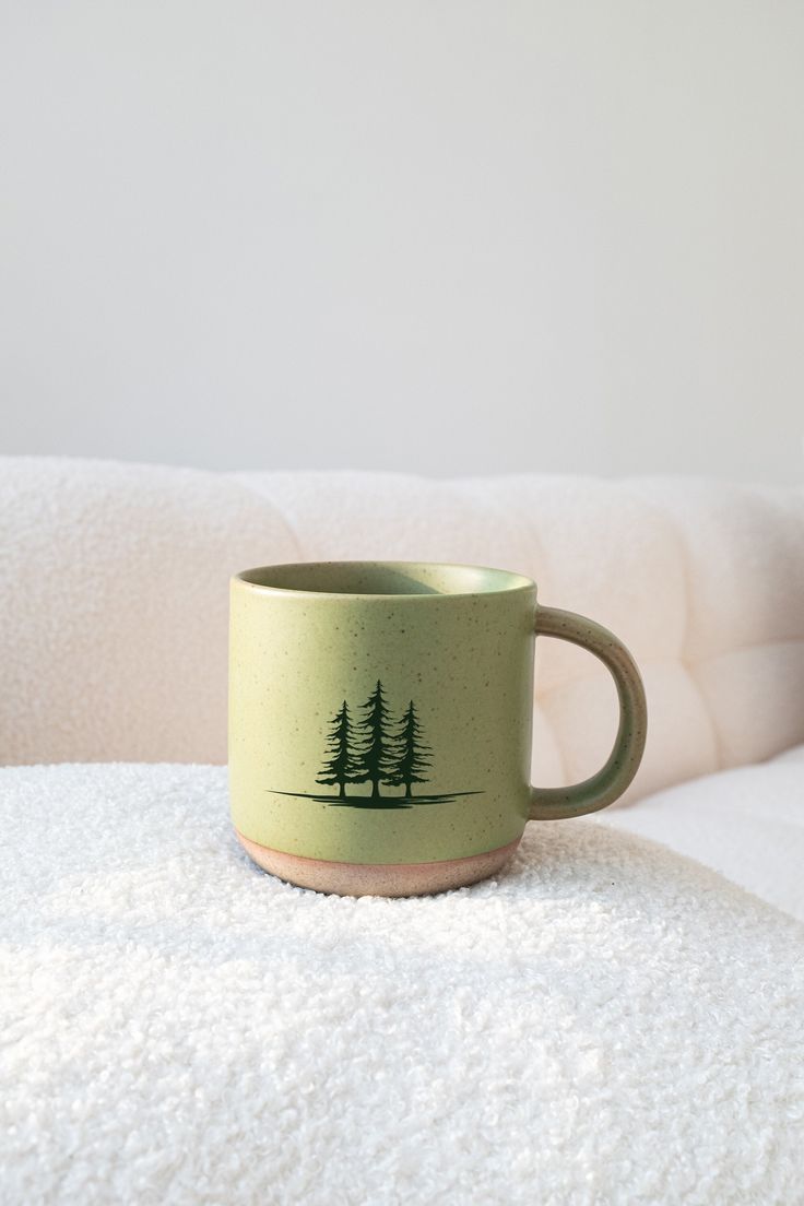 a green coffee cup sitting on top of a white blanket