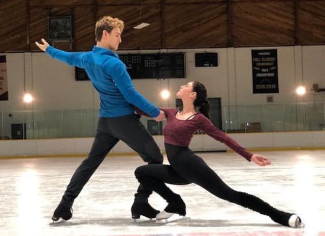 two people are skating on an ice rink