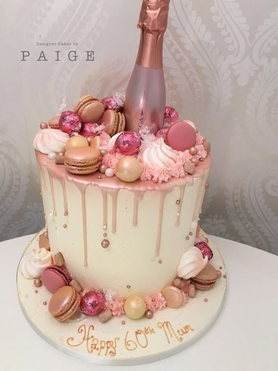 a birthday cake with a bottle of champagne on top and lots of candies around it