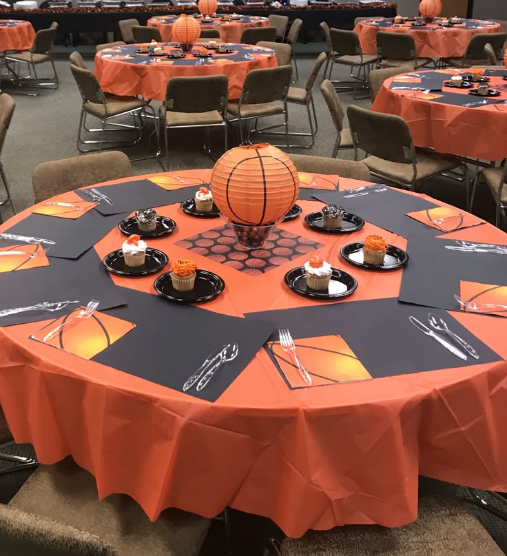 an orange and black round table with cupcakes on it