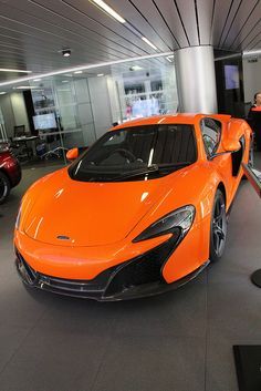 an orange sports car parked in a showroom