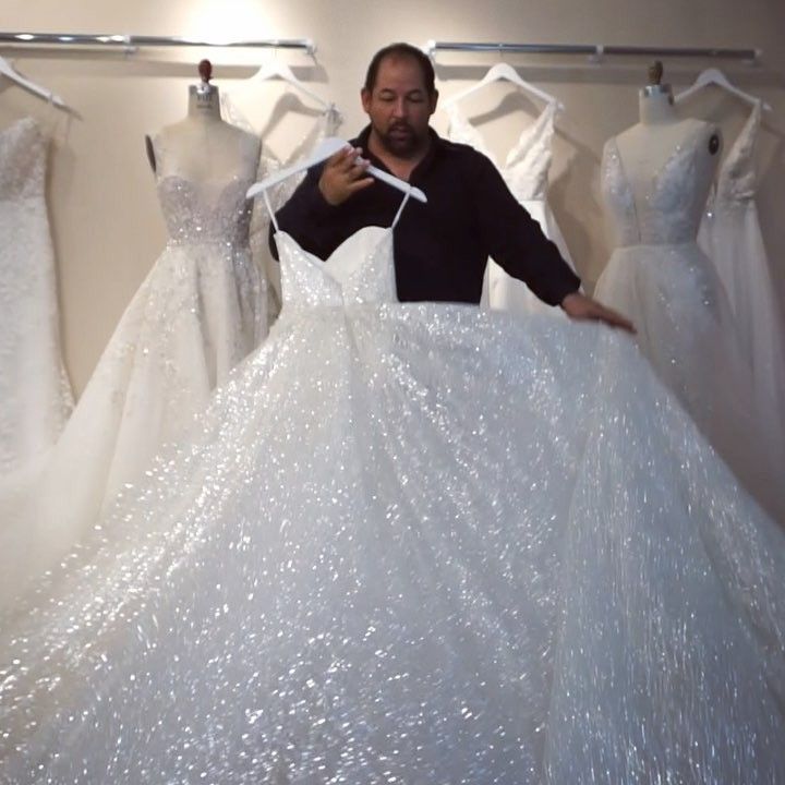 a man standing in front of some white dresses