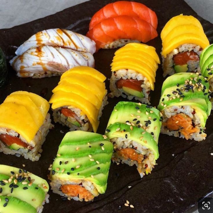 sushi on a black plate with various toppings