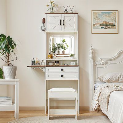 a bedroom with a white bed, desk and mirror on the wall next to it