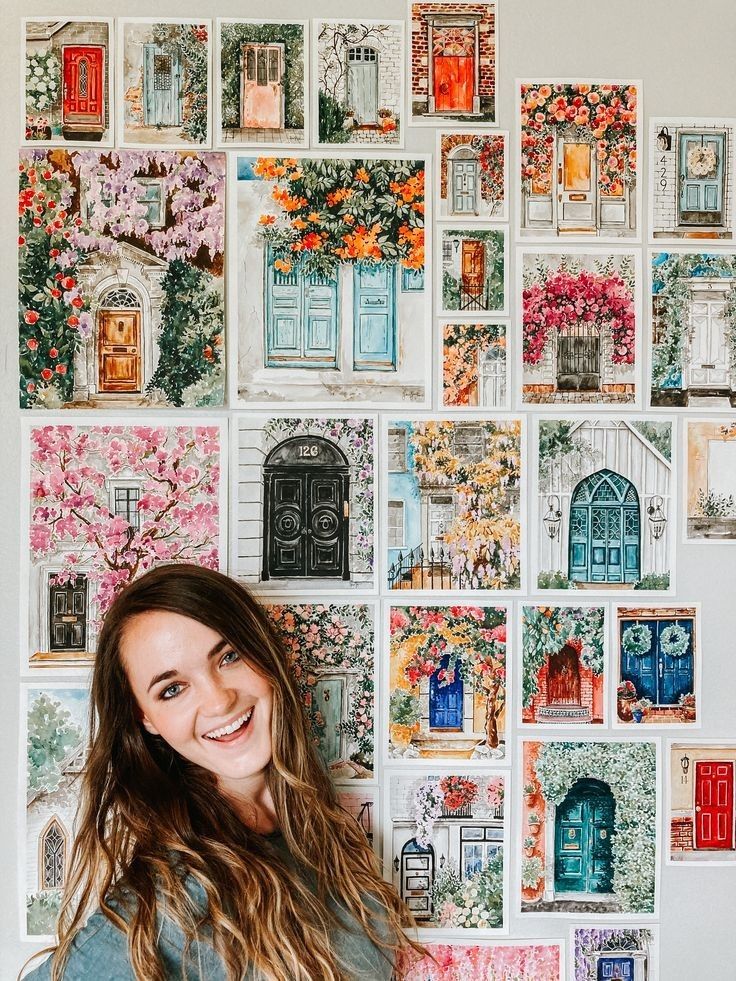 a woman standing in front of a wall with many pictures on it and smiling at the camera