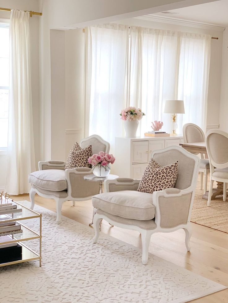 a living room filled with white furniture and flowers in vases on top of tables