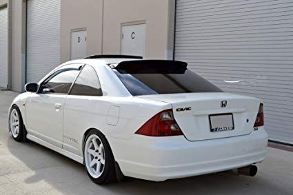 the rear end of a white car parked in front of a garage with roller doors