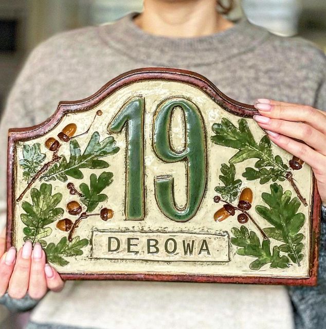 a woman holding up a plaque with the number 19 on it and acorns