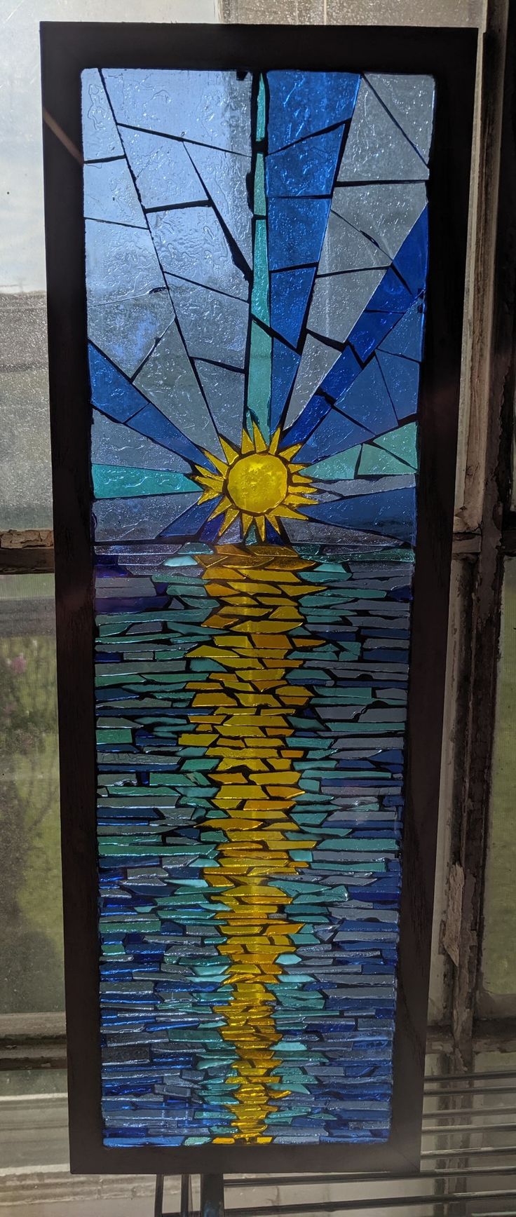 a stained glass window with the sun reflecting in water