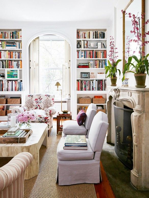 a living room filled with furniture and bookshelves next to a fire place in front of a window