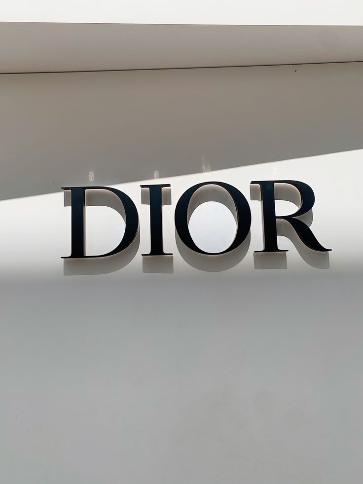 the word dior is placed on top of a white wall with black letters in front of it