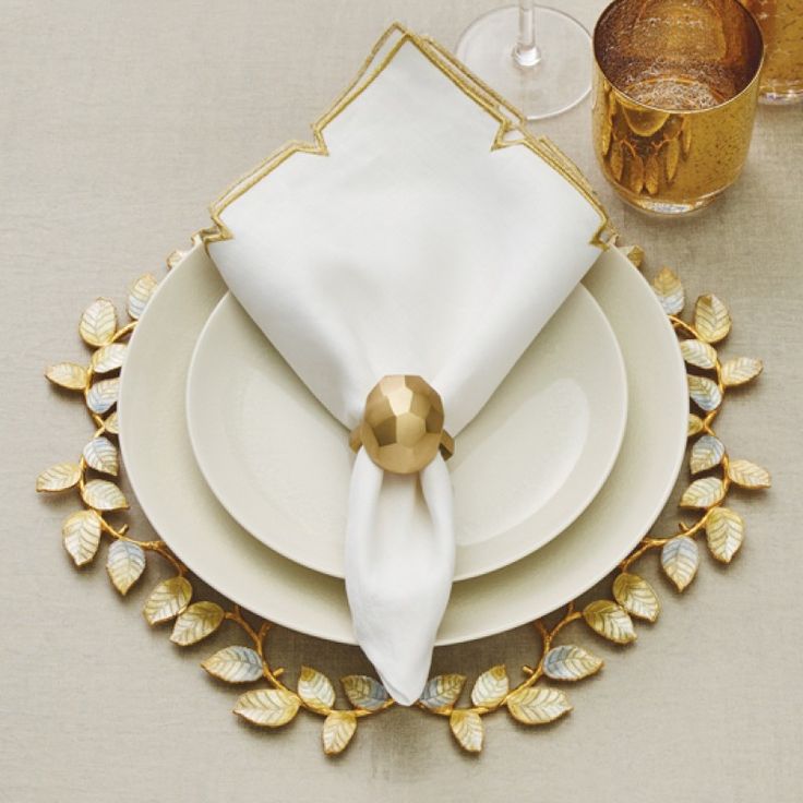 a place setting with white plates and gold napkins