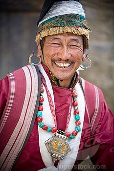 an old man with a smile on his face and beads around his neck is smiling for the camera