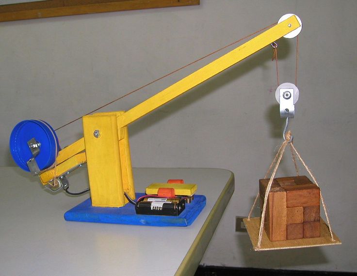 a toy crane is attached to a wooden box on a table with other toys in front of it