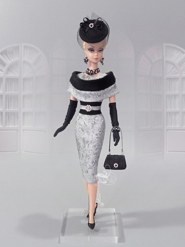 a barbie doll wearing a black and white dress with gloves, purse and hat on display