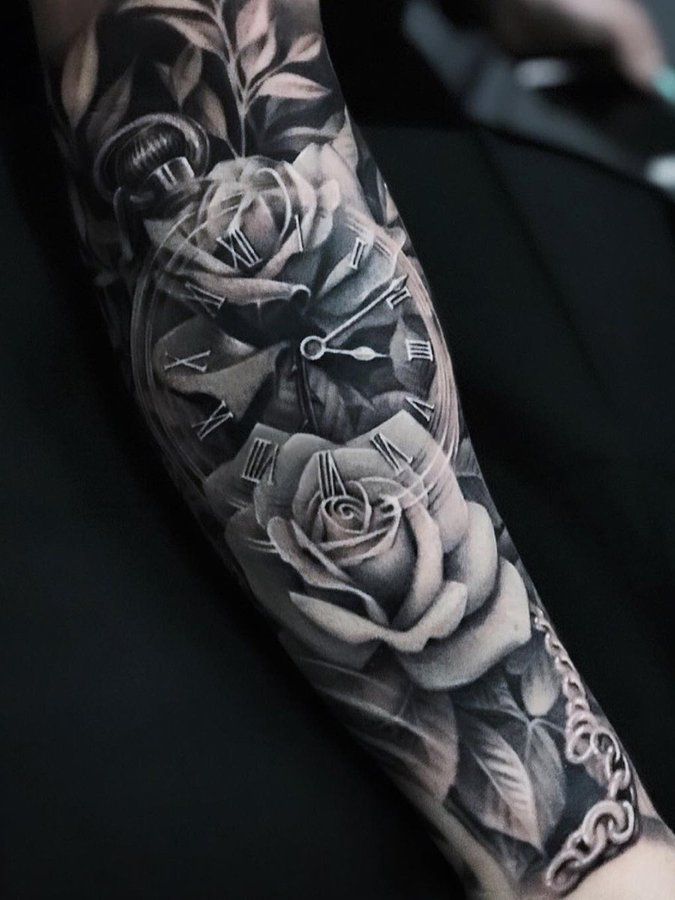 a black and white photo of a clock with roses on it's arm, next to a keyboard