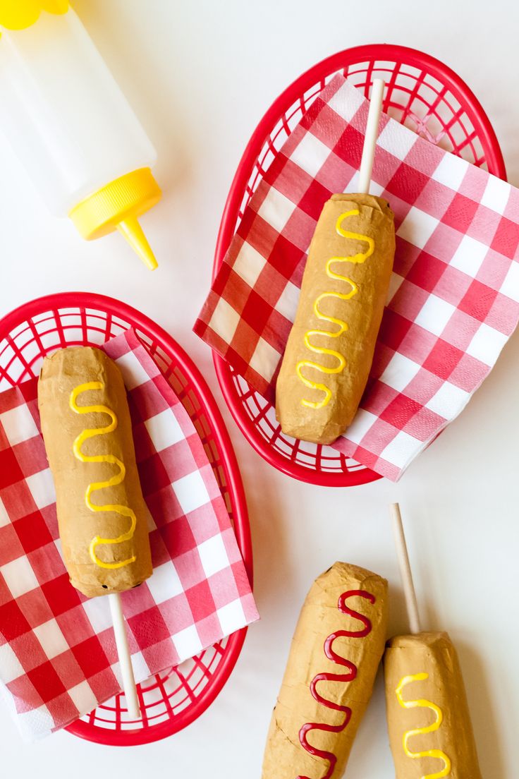 two hotdogs with ketchup and mustard on them sitting in red baskets