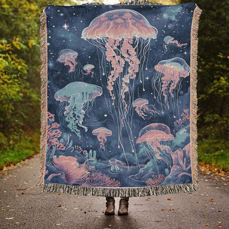 a person holding up a blanket with jellyfishs on it in the middle of a road