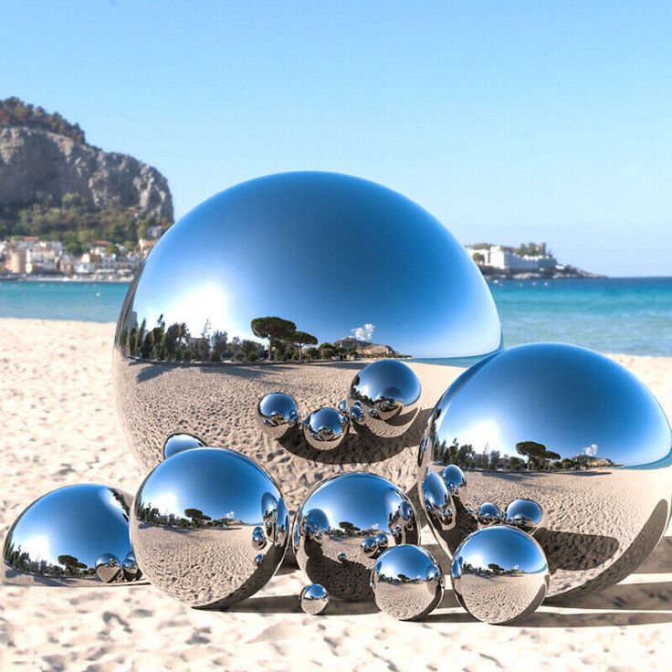 a bunch of shiny balls sitting on top of a sandy beach