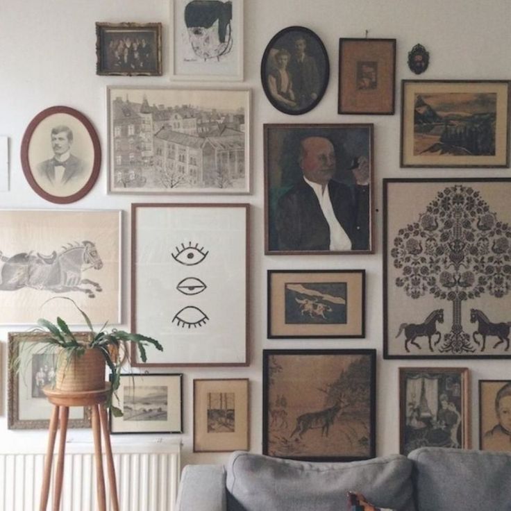 a living room filled with lots of framed pictures on the wall next to a couch