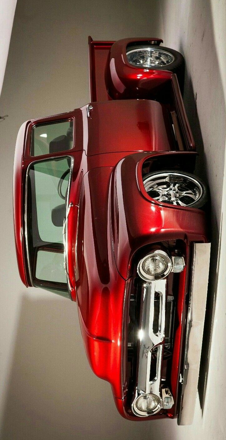 the front end of a red sports car parked in a garage next to a wall