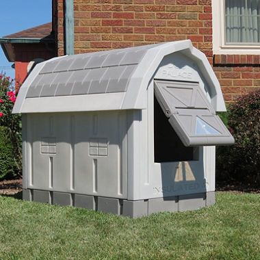 a gray mailbox sitting in the grass next to a brick building