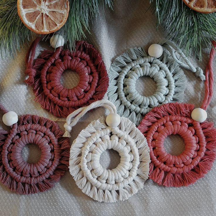 four pieces of yarn and oranges on a white table cloth with pine branches in the background