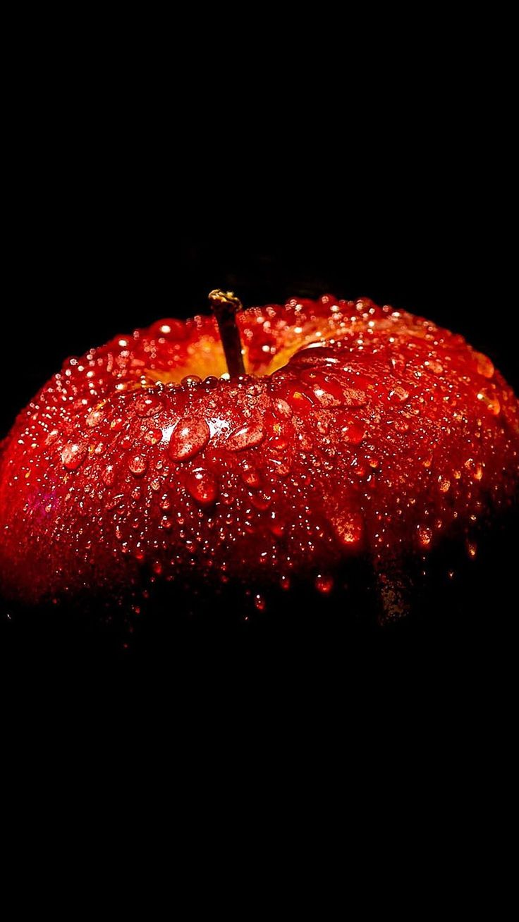 an apple with water droplets on it is shown in the dark, and has a black background