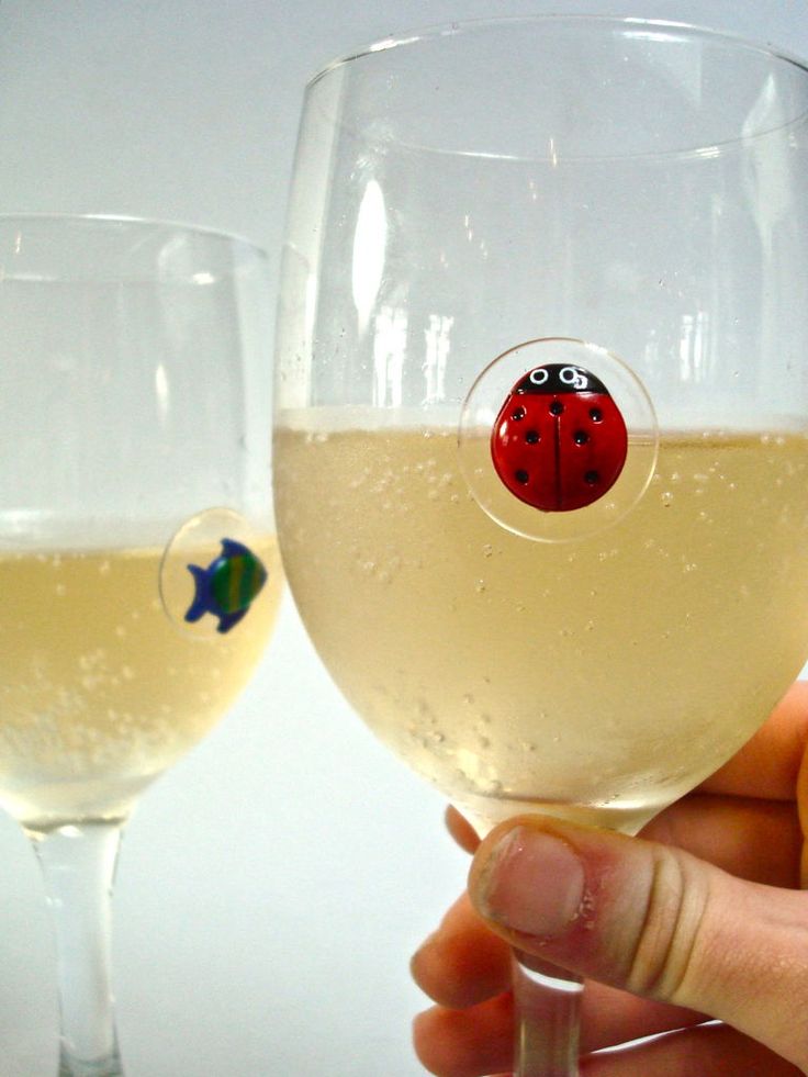 a ladybug on the side of a wine glass is being held by someone