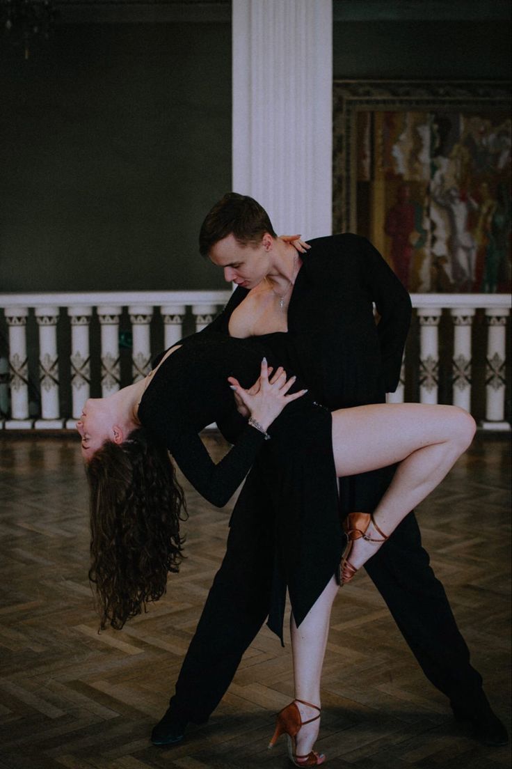 two people are dancing on the floor in a dance studio, one is holding the other's leg